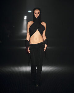 Model walking for P.L.N wearing black criss cross top with hood during Copenhagen Fashion Week AW23