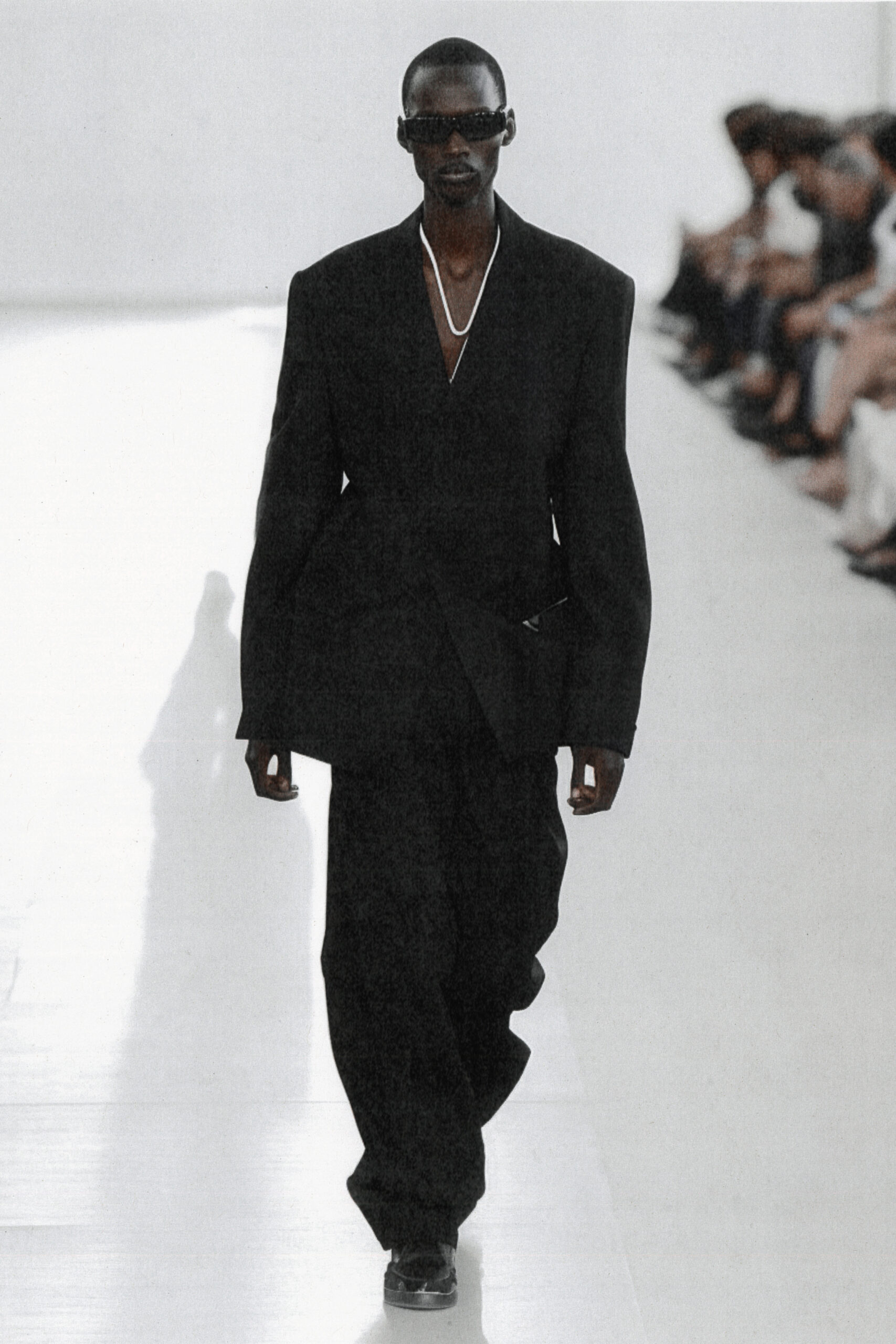 Model iført Heliot Emil sort jakkesæt under Paris Fashion Week SS24 brugt AI